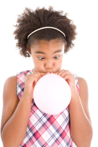 Girl blowing up a pink balloon.